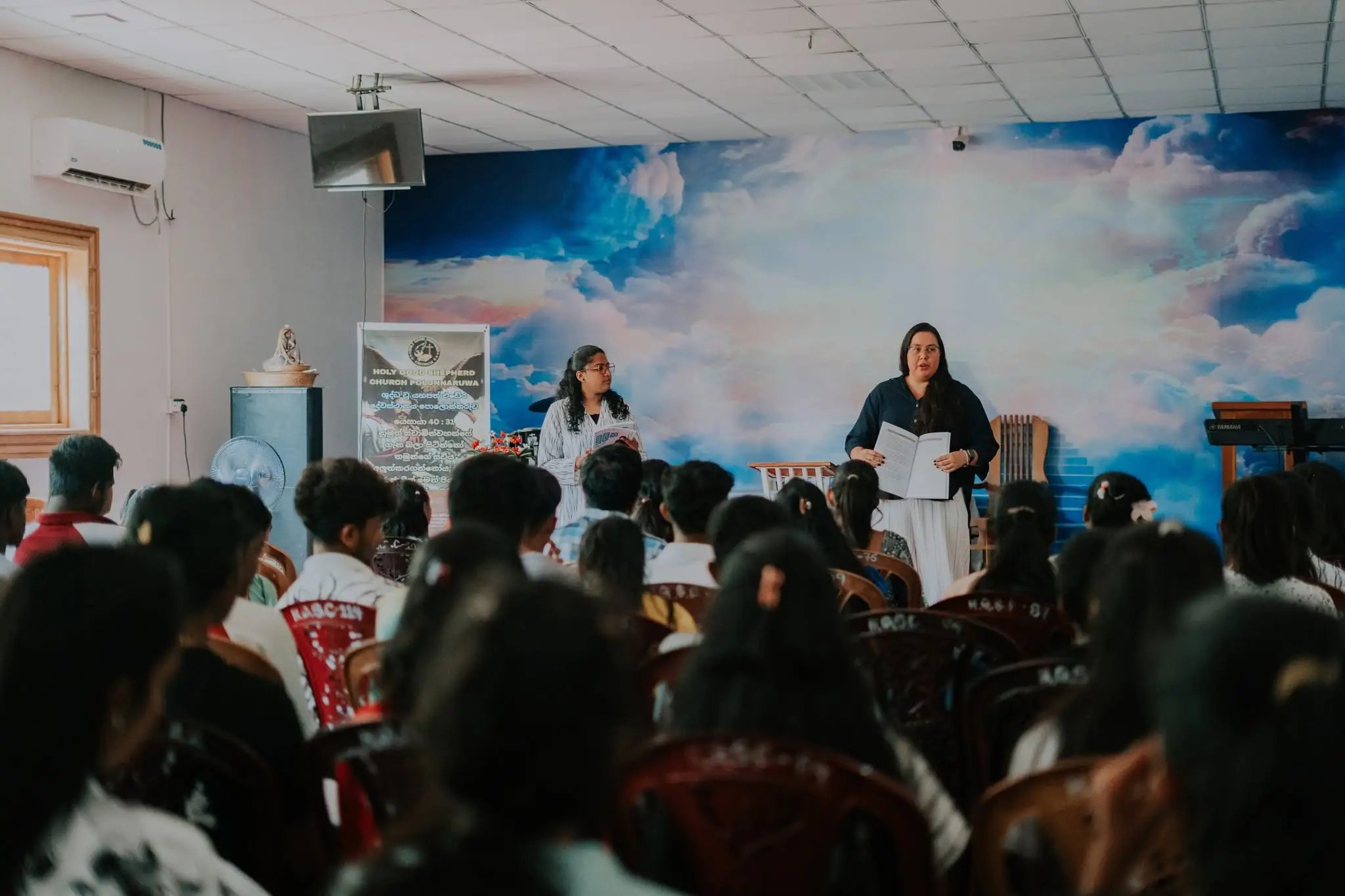 A gathering in a hall, a speaker at the front and the room full
